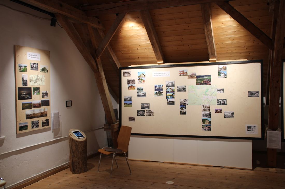 Zwei Tafeln mit Fotos und eine Station mit einem Tablet